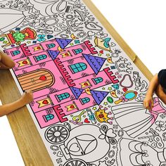 two children are drawing on a large piece of paper with colored pencils and markers