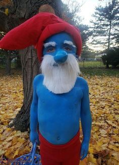 a man in blue and red is standing next to a tree