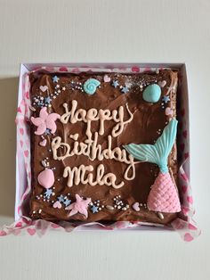 a birthday cake with chocolate frosting in a pink box that says happy birthday mia