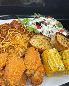 a white plate topped with fried chicken, pasta and corn on the cob