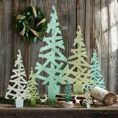 paper cut christmas trees sitting on top of a table next to a wreath and other decorations