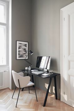 a desk with a laptop on top of it in front of a window and an open door