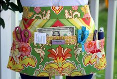 a woman is wearing an apron with money in the pocket and scissors on her hip