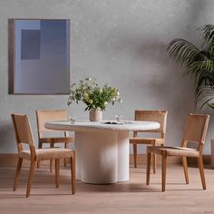 a white table with four chairs around it and a potted plant in the middle