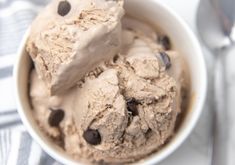 two scoops of ice cream with chocolate chips in a white bowl on a table