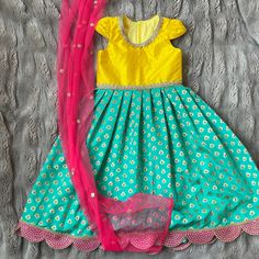 Anarkali gown for babies, toddlers, and girls This yellow raw silk and teal brocade anarkali gown features god trim at neck and waist and standout pink and gold scallop trim at the hem of the dress. Unique racer back with zipper closure makes that dress easy to get in and out of. This dress is fully lined in a soft cotton so there is nothing itchy, scratchy, or uncomfortable against your child's skin. Contrasting pink sequin net dupatta adds extra color and glamor to this outfit! Outfits are ful Yellow Anarkali Art Silk Churidar, Yellow Anarkali Dress With Zari Work, Yellow Anarkali Dress With Dori Work, Yellow Traditional Drape Dress For Eid, Yellow Dress With Pallu For Eid, Traditional Drape Yellow Dress For Eid, Yellow Dress With Traditional Drape For Festive Occasion, Yellow Festive Dress With Traditional Drape, Yellow Dress With Zari Work For Diwali