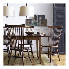 a dining room table and chairs with pictures on the wall