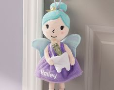 a doll hanging on the door handle with money in it's hand and wearing a purple dress