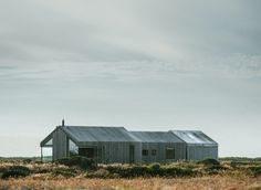 a small house sitting on top of a grass covered field in the middle of nowhere