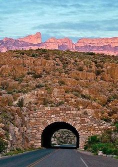 a road going into a tunnel with mountains in the background