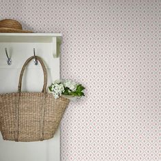 a wicker basket hanging on the wall next to a white door with flowers in it