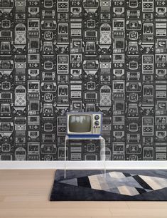 an old fashioned television sitting on top of a rug in front of a wallpaper