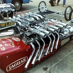 a red car engine sitting on top of a flatbed truck with chrome exhaust pipes