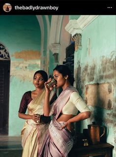 two women standing next to each other near a wall