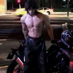 a shirtless man standing next to a motorcycle