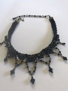 Black is beautiful in this Classic color. This is a hand beaded choker made with hand painted resin flowers and constructed with glass beads on a sturdy fabric backing. With seven handbeaded swags hanging down. A smashing black choker that will get you noticed. This is a quality piece of jewelry that will last a life time. Created by designer Colleen Toland who has been creating her unique style of vintage jewelry for more than 30 years. All of our pieces come with an engraved tag with Colleen's Bohemian Black Beaded Necklaces With Bead Caps, Party Choker With Dangling Beads, Vintage Beaded Choker For Party, Festival Beaded Dangle Choker, Vintage Black Beads Choker Gift, Gothic Beaded Choker For Festivals, Gothic Handmade Adjustable Beaded Necklaces, Handmade Adjustable Gothic Beaded Necklaces, Vintage Adjustable Beaded Choker