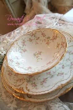 a stack of plates sitting on top of a table next to a white and gold plate