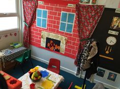 a child's playroom with red brick wall and blue carpeting, colorful furniture