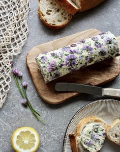 a loaf of bread with flowers on it next to sliced lemons and lavender sprigs