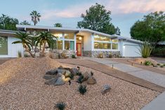 a house that is in the middle of some rocks and gravel with trees around it