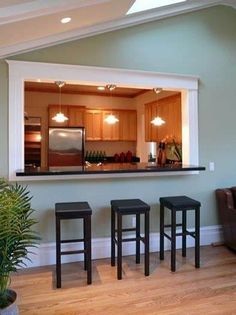 a living room with three stools and a kitchen in the backround behind it