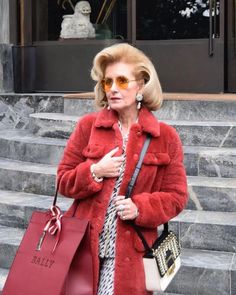 a woman in a red fur coat carrying shopping bags