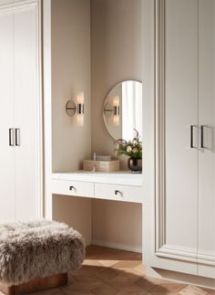 a white dressing table with a stool and mirror on it in a room that has beige walls