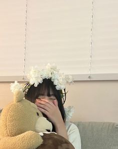 a woman covering her face with a teddy bear