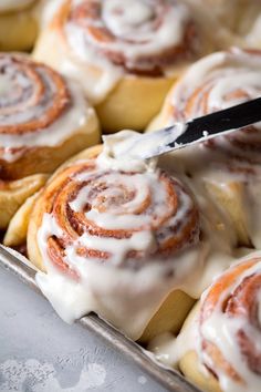 a pan filled with cinnamon rolls covered in icing