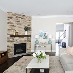 a living room filled with furniture and a fire place in front of a stone wall