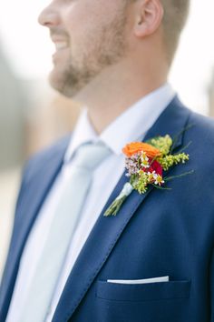 a man in a blue suit with an orange boutonniere