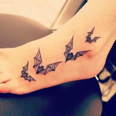 a small tattoo on the foot of a person with bats and cobwes