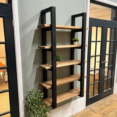 a room that has some shelves on the wall with plants in it and two doors leading to another room