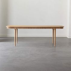 a wooden table sitting on top of a floor next to a white wall in an empty room