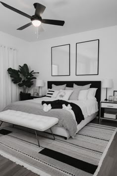 a black and white photo of a bedroom with a large bed, two framed pictures on the wall