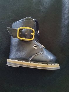 a close up of a pair of shoes on a black surface with a yellow buckle