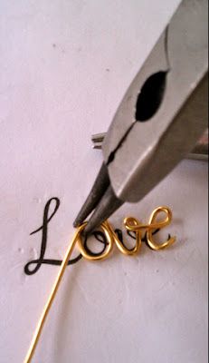 a pair of scissors cutting the word love out of paper with gold colored metal wire