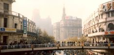 people are walking on a bridge over a city street