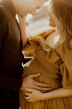 a man and woman standing next to each other with their hands on their stomachs