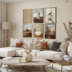 a living room filled with white furniture and pictures on the wall above it's coffee table