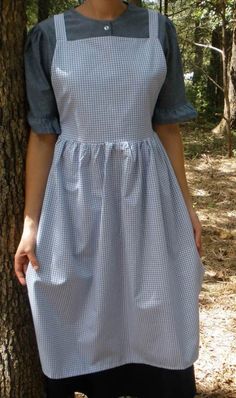 a woman standing next to a tree wearing an apron