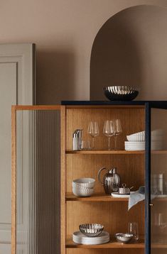 a wooden cabinet filled with dishes and wine glasses