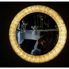 a person taking a selfie in front of a round mirror with lights on it