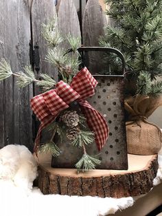 a metal box with pine cones and a bow on it sitting next to a christmas tree