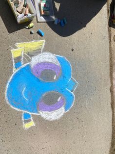 a child's drawing on the sidewalk with chalk and crayons next to it