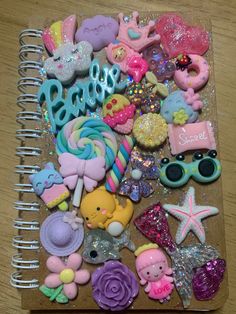 a spiral notebook covered in lots of different types of candies and other things on top of a wooden table