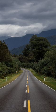 an empty road in the middle of nowhere with mountains in the background