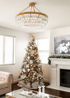 a living room with a christmas tree in the corner and a chandelier hanging from the ceiling