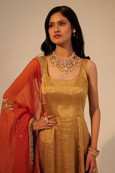 Gold metallic anarkali with square back and dark gold border. Paired with contrast rust dupatta with cut dana, bead, sequin and zari embroidery.
Components: 2
Pattern: Embroidered
Type Of Work: Zari, Sequin, Cut Dana and Bead Work
Neckline: Square Neck
Sleeve Type: Sleeveless
Fabric: Handwoven Tissue, Silk Cotton, Organza
Color: Gold
Other Details: 
Attached lining
Kiran lace dupatta border
Round back
Weight: 3 kgs
Occasion: Mehendi and Haldi - Aza Fashions Anarkali With Dupatta, Dupatta Border, Zari Embroidery, Gold Border, Dark Gold, Anarkali, Aza Fashion, Sleeve Type, Square Neck