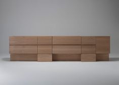 a wooden shelf sitting on top of a white floor next to a wall with multiple pieces of wood in it